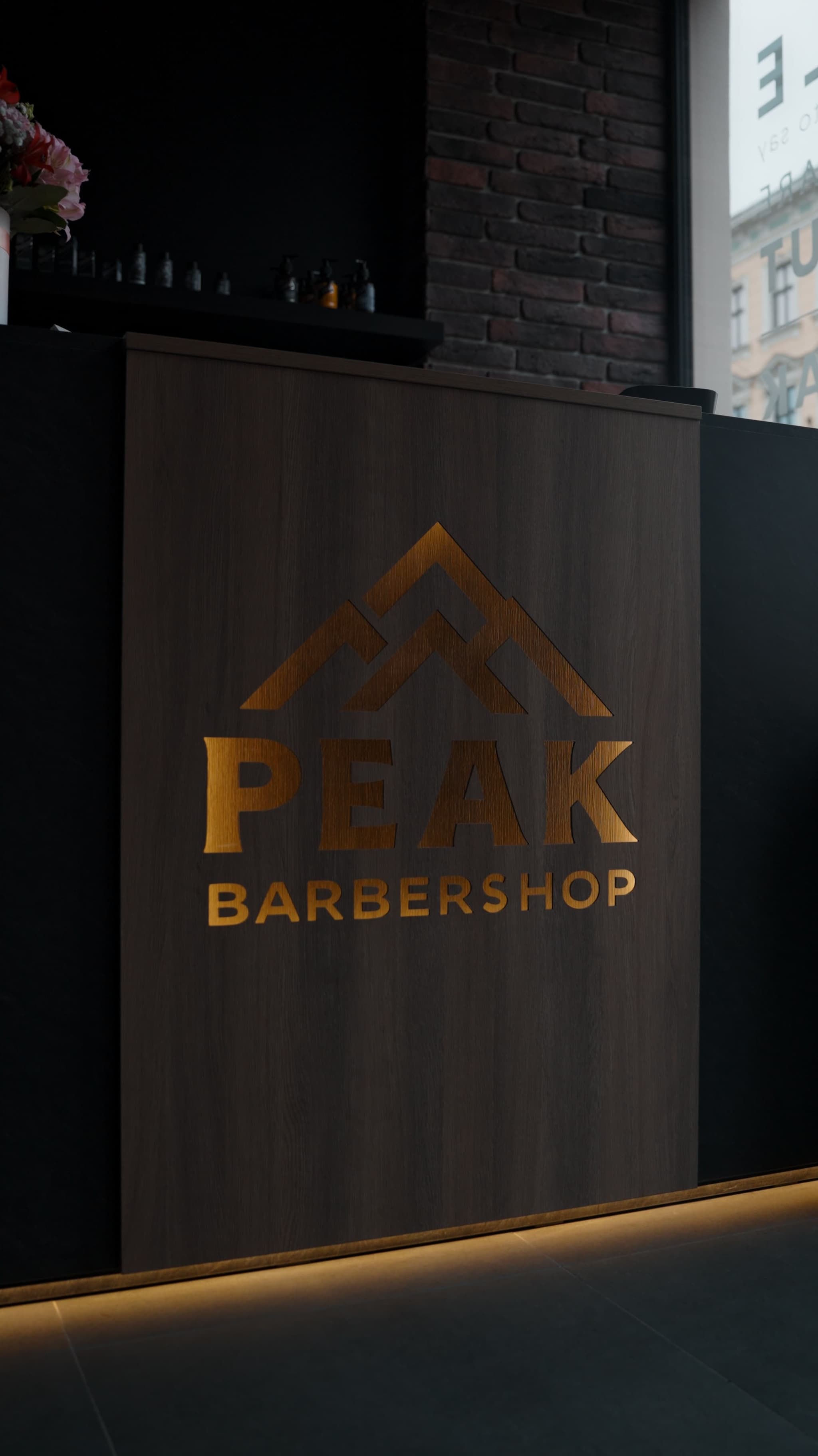Стойка регистрации Peak Barbershop с золотым логотипом в Риге